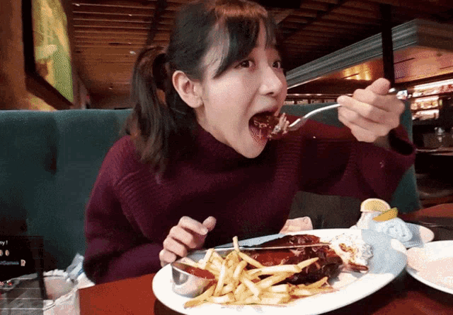 a woman is eating a plate of food with a fork in her mouth