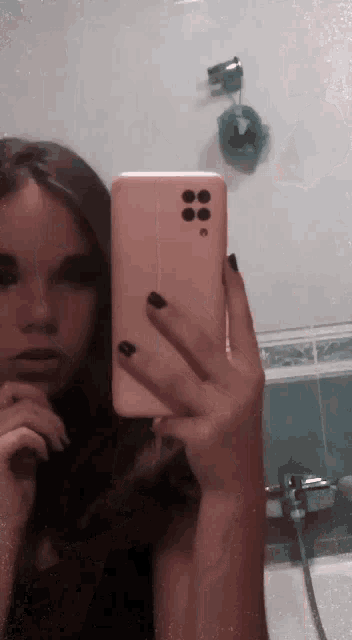 a woman taking a picture of herself in a bathroom mirror
