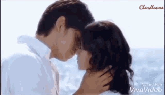 a man and a woman are kissing on the beach near the ocean .