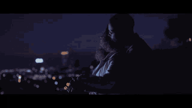 a man and a woman are hugging at night with a city in the background