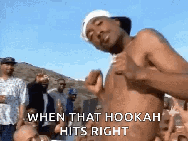 a man without a shirt is dancing in front of a crowd of people .