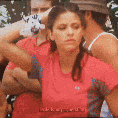 a woman in a red under armour shirt is surrounded by men .