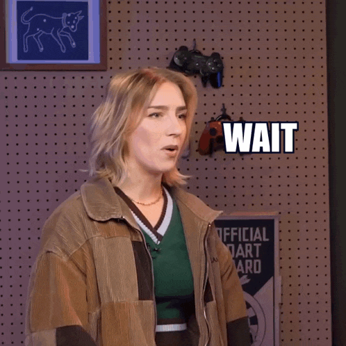 a woman is standing in front of a wall that says wait wait