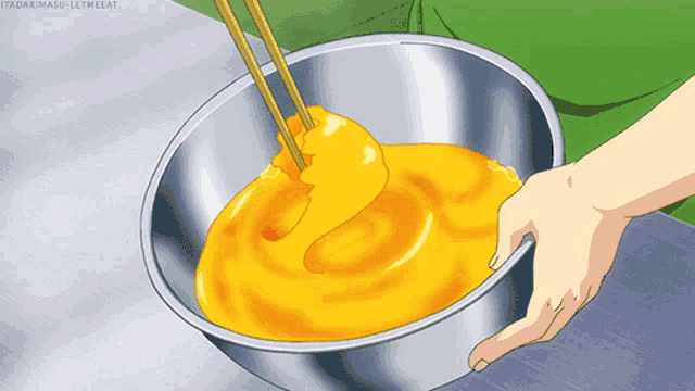 a person is mixing a yellow liquid in a metal bowl with chopsticks