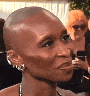 a close up of a woman 's face with a shaved head and earrings