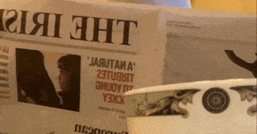 a cup sits next to a newspaper that says " the eht " on it