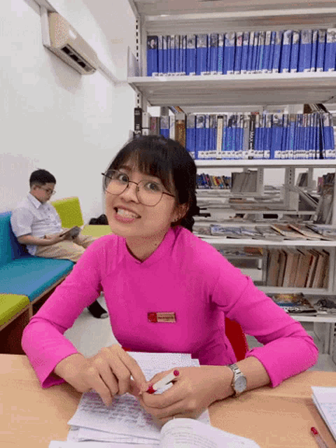 a woman wearing glasses and a pink shirt has a name tag on her chest that says " nguyen "