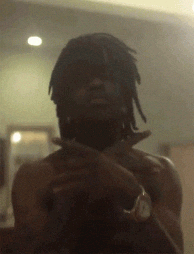 a shirtless man with dreadlocks and a watch around his neck