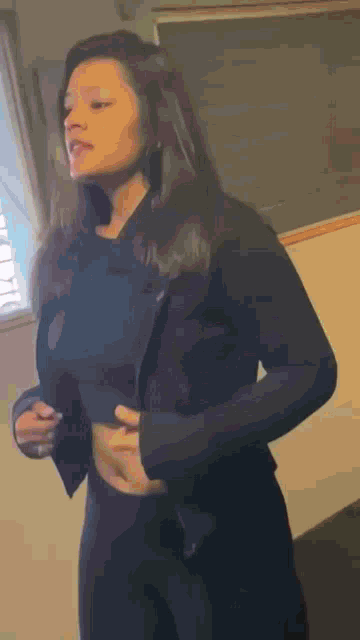 a woman wearing a black jacket and black pants is standing in a room .