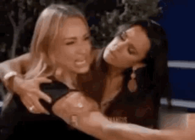 two women are hugging each other and one of them is making a face .