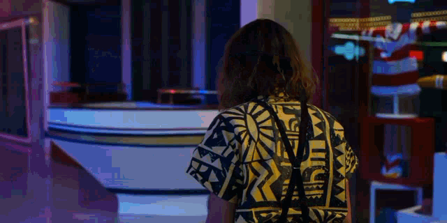 a woman wearing a yellow and black shirt with a geometric pattern on the back
