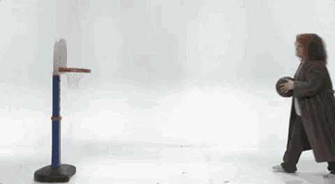 a woman in a coat is throwing a basketball in a hoop