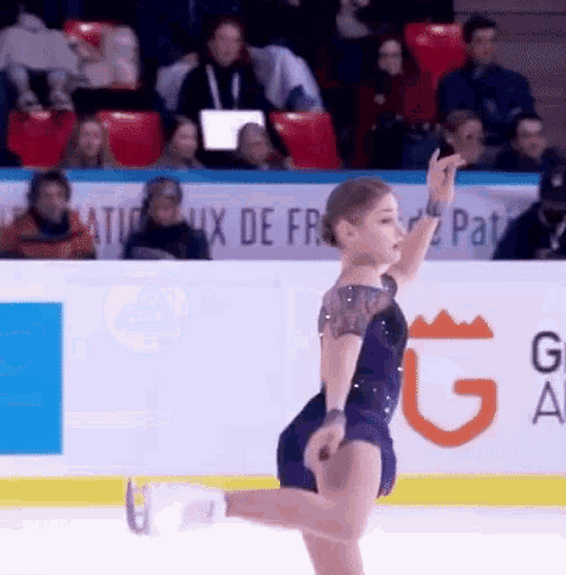 a woman in a purple dress is ice skating in front of a sign that says g.