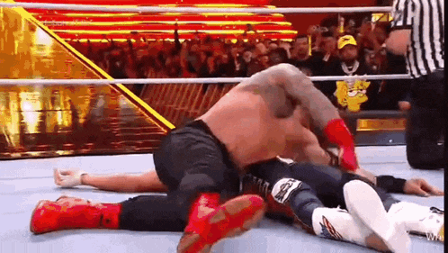 two men are wrestling in a wrestling ring while a referee looks on .