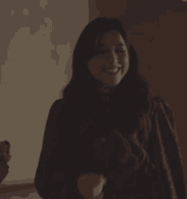 a woman in a black shirt is smiling and dancing in a room .