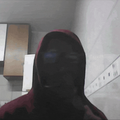 a man in a red hoodie is standing in front of a wall