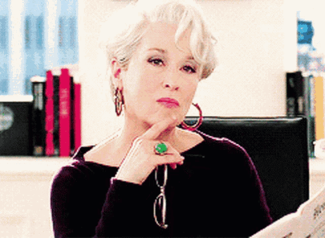 a woman with a green ring on her finger is reading a magazine