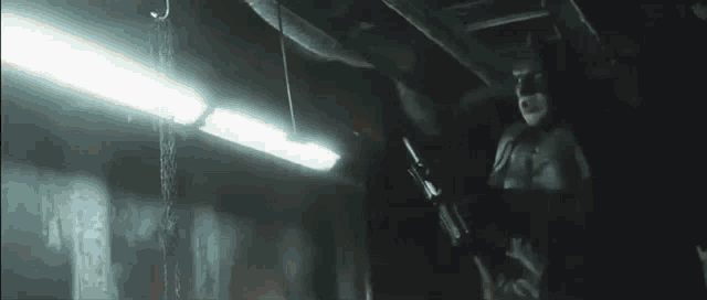 a man in a batman costume is standing in a dark room with a torch .