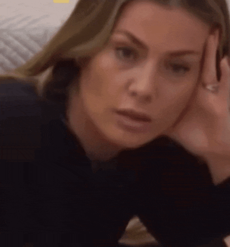 a woman is sitting on a couch with her hand on her head .