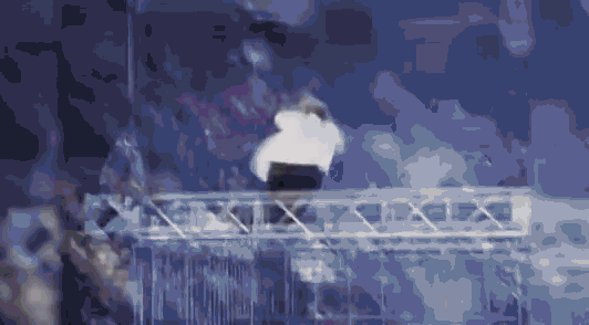 a man is standing on a metal structure in front of a crowd of people .