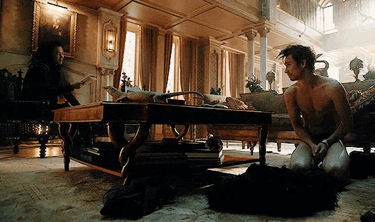 a man is kneeling on the floor in a living room while a woman sits at a table