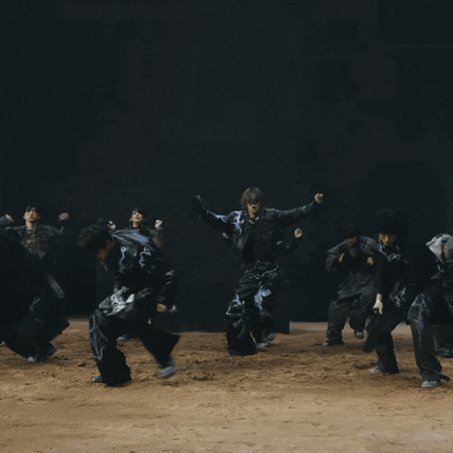 a group of people are dancing in a dark room and one of them is wearing a belt that says he