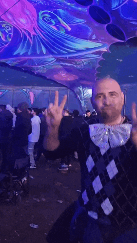 a man giving a peace sign in front of a crowd of people