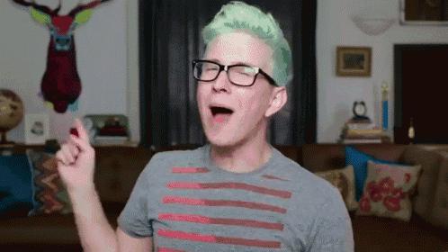 a man with green hair wearing glasses and a grey shirt