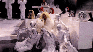 a group of mannequins are sitting in front of a woman playing a yamaha keyboard