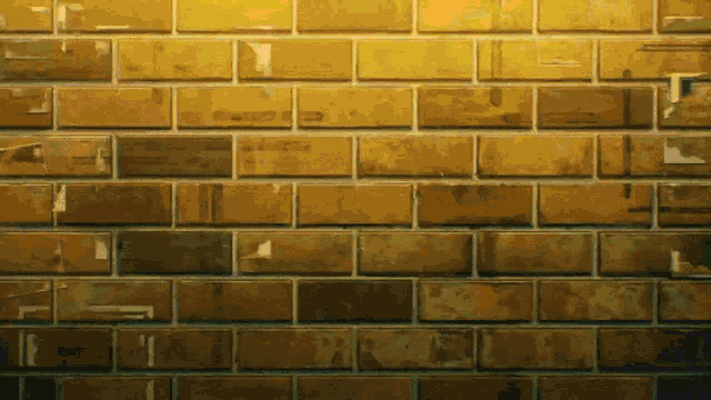 a close up of a brick wall with a few bricks that are yellow