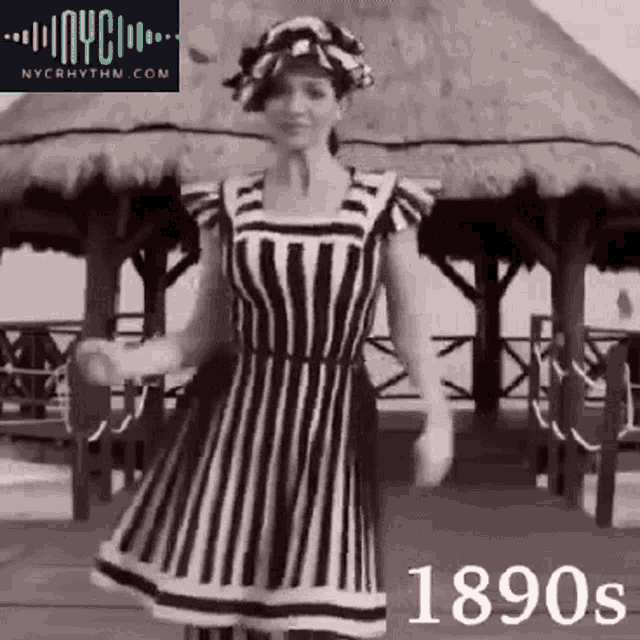 a black and white photo of a woman in a striped dress and hat .