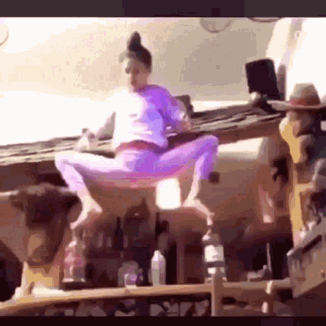 a woman is sitting on the roof of a building holding a bottle of alcohol .