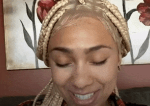 a woman with braids in her hair is smiling with her eyes closed .