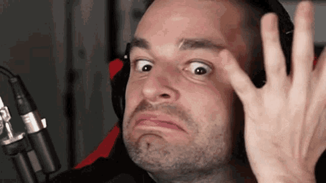 a man wearing headphones is making a funny face in front of a microphone while making a funny face .
