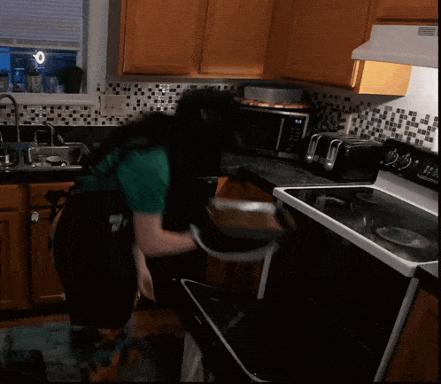 a person cooking in a kitchen with a clock on the stove that reads 9:41