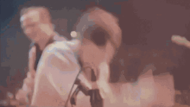 a blurry picture of a man playing a guitar in front of a crowd at a concert .