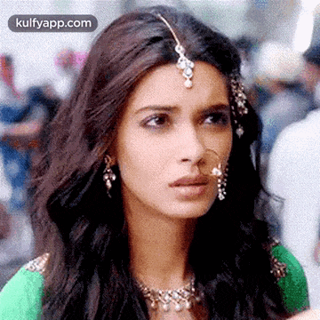 a close up of a woman wearing a nose ring , earrings , and a headpiece .