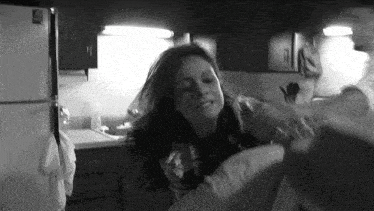 a black and white photo of a woman standing in a kitchen