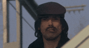 a man with a mustache wearing a flat cap