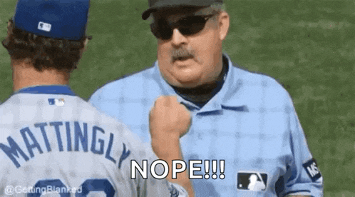 a baseball player is talking to a referee who is holding his fist up .
