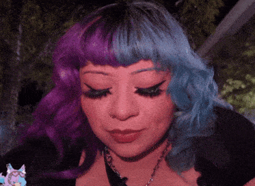 a woman with purple and blue hair has a cat sticker on her neck