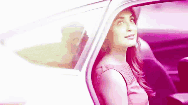a woman is sitting in the back seat of a car and smiling .