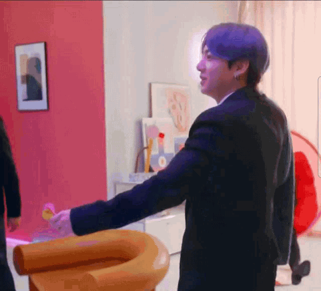 a man in a suit is standing next to a wooden chair in a living room .