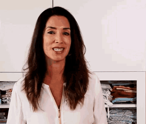 a woman in a white shirt is standing in front of a closet filled with clothes .