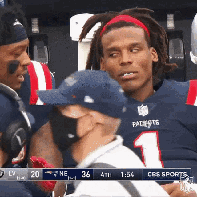 a patriots football player talks to a man wearing a face mask