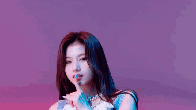 a close up of a woman making a shhh gesture with her finger .