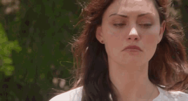 a close up of a woman 's face with a white shirt on