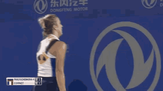 a woman is holding a tennis racquet in front of a sign that says " dong "