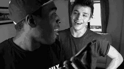 a black and white photo of two young men talking to each other .