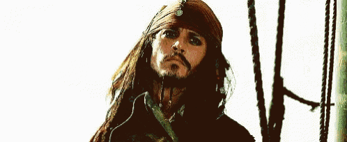 a man with long hair and a beard is standing on a boat wearing a bandana .